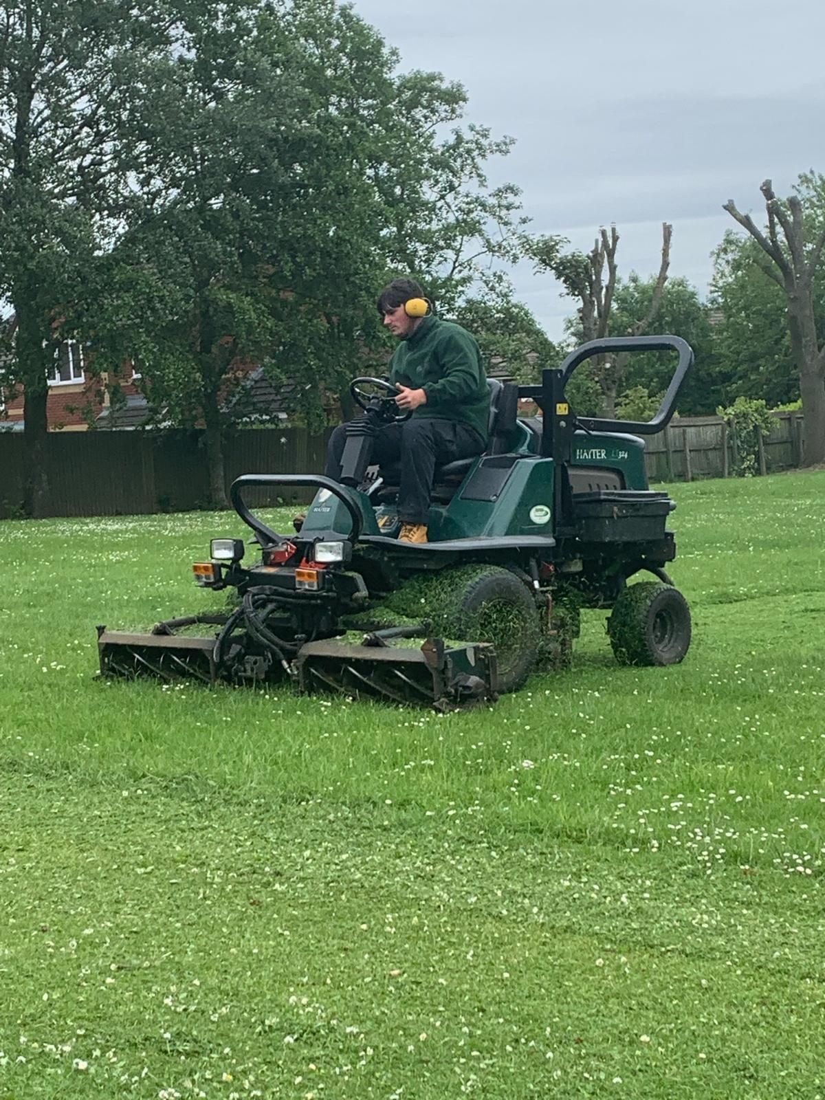 A man is riding a lawn mower on a lush green field.