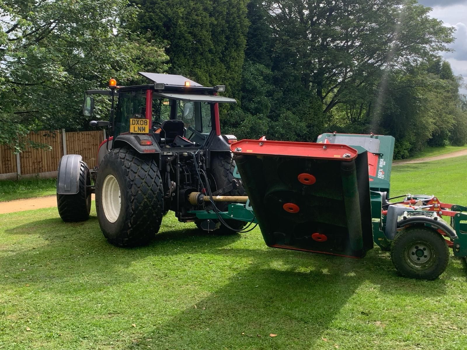 A tractor is parked in a grassy field with a trailer attached to it.