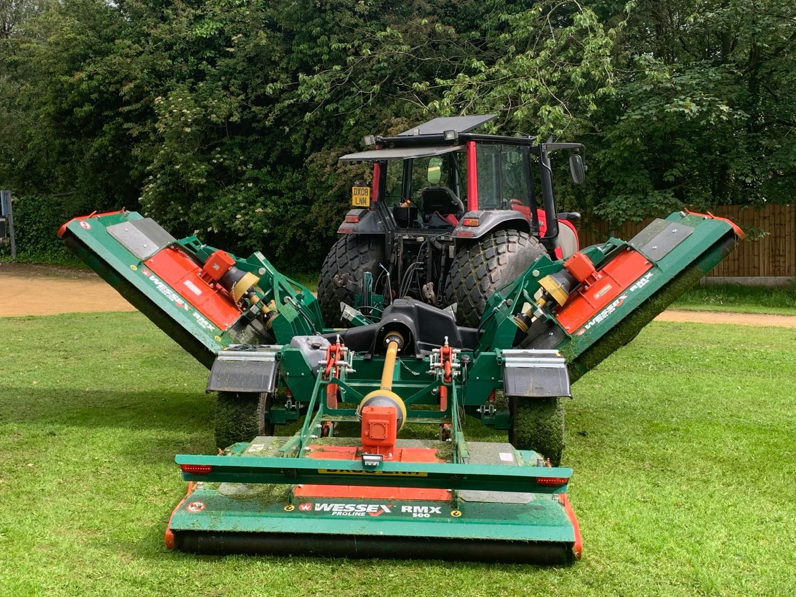 A green and red tractor is sitting on top of a lush green field.