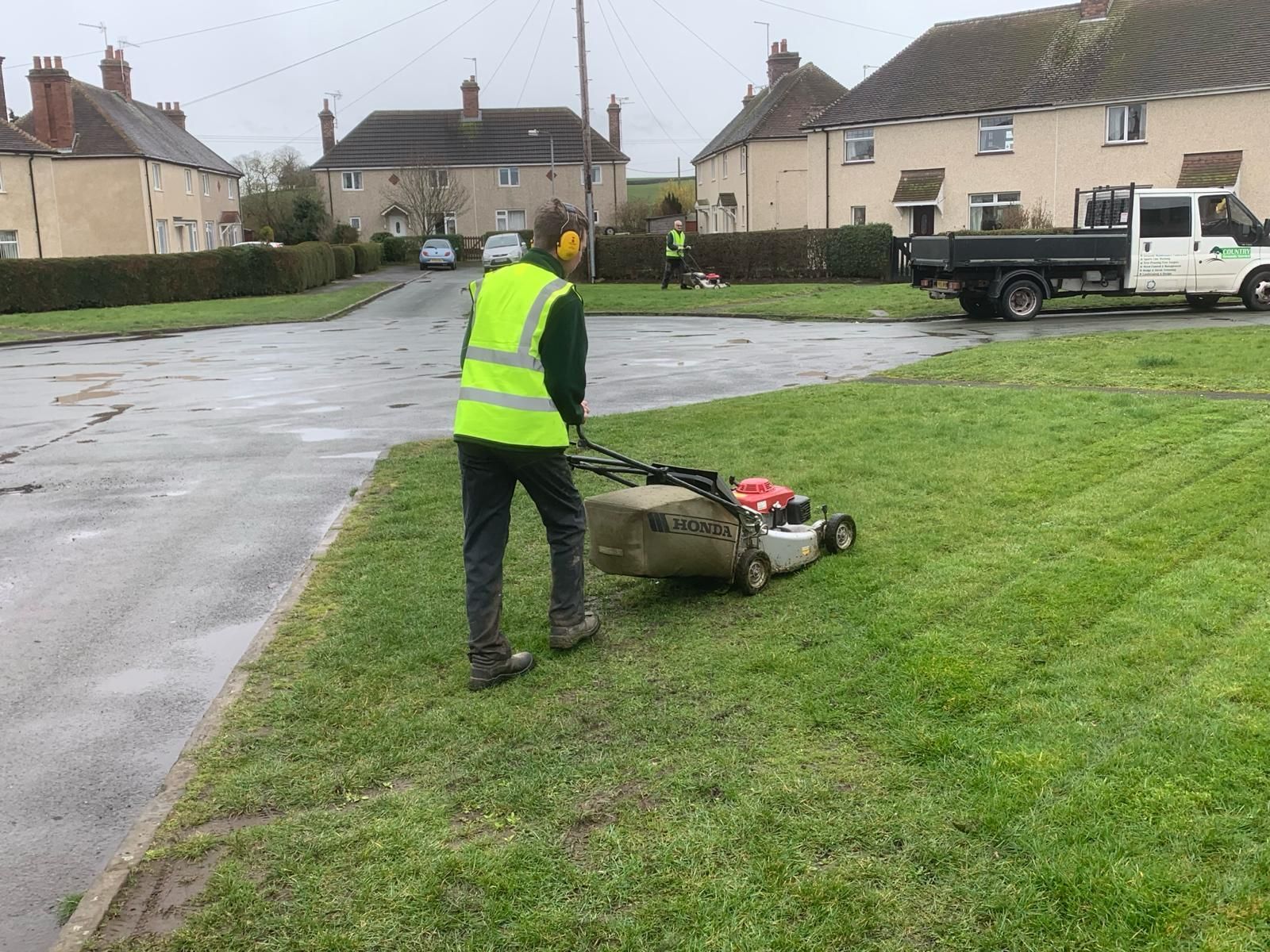 A man is using a lawn mower to cut the grass in a residential area.