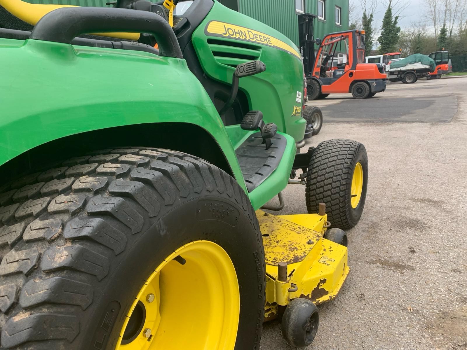 A green and yellow john deere lawn mower is parked in a parking lot