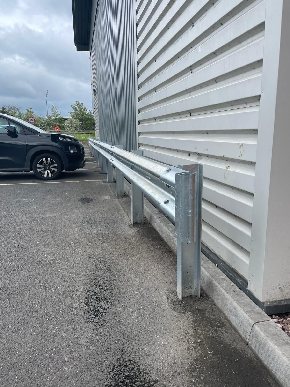 A car is parked in front of a building with a metal railing.