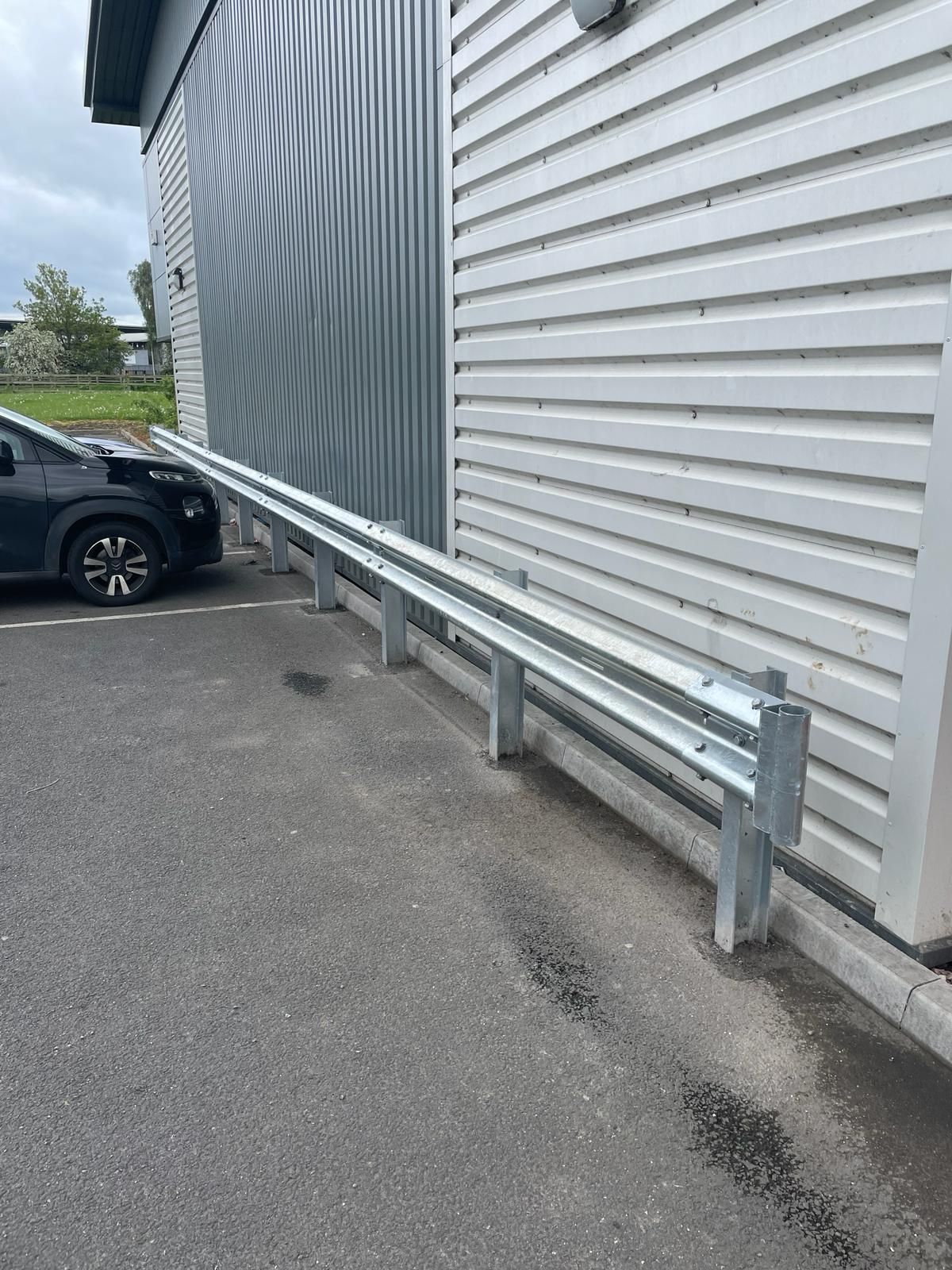 A car is parked in front of a building with a metal railing.