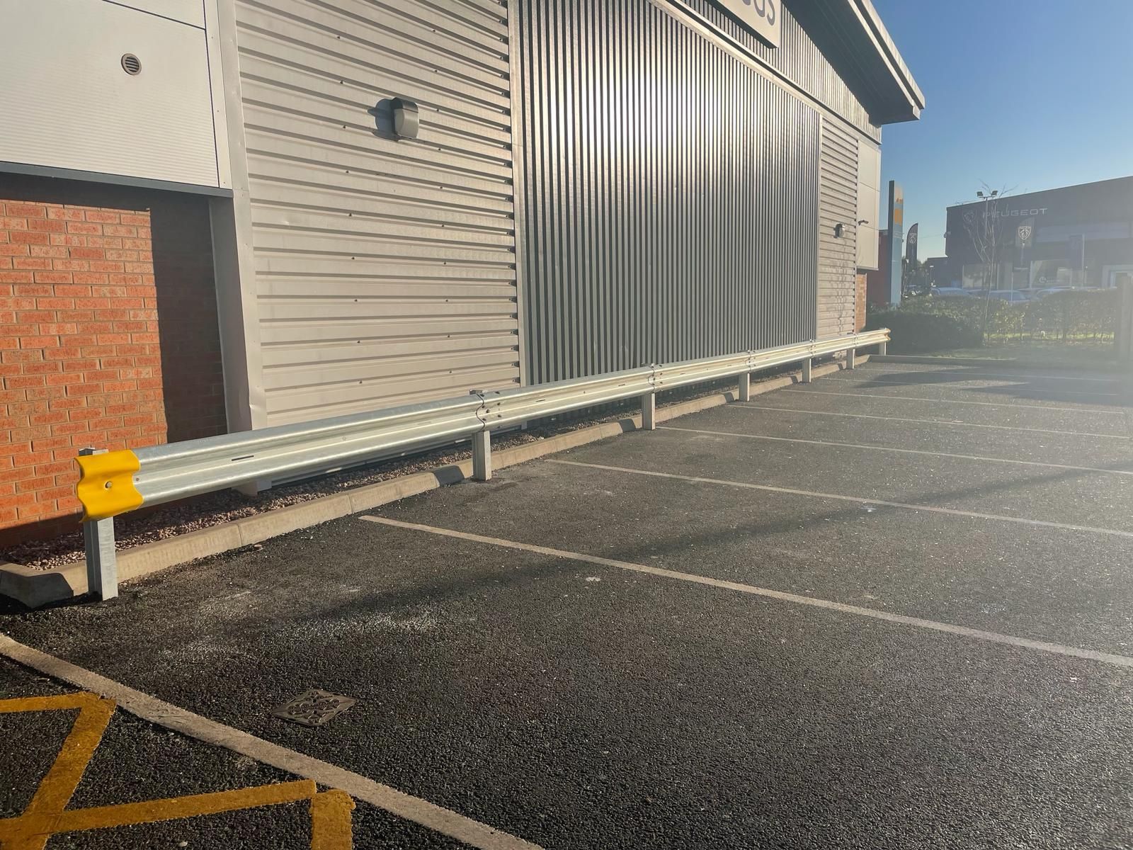 A parking lot in front of a building with a metal barrier.