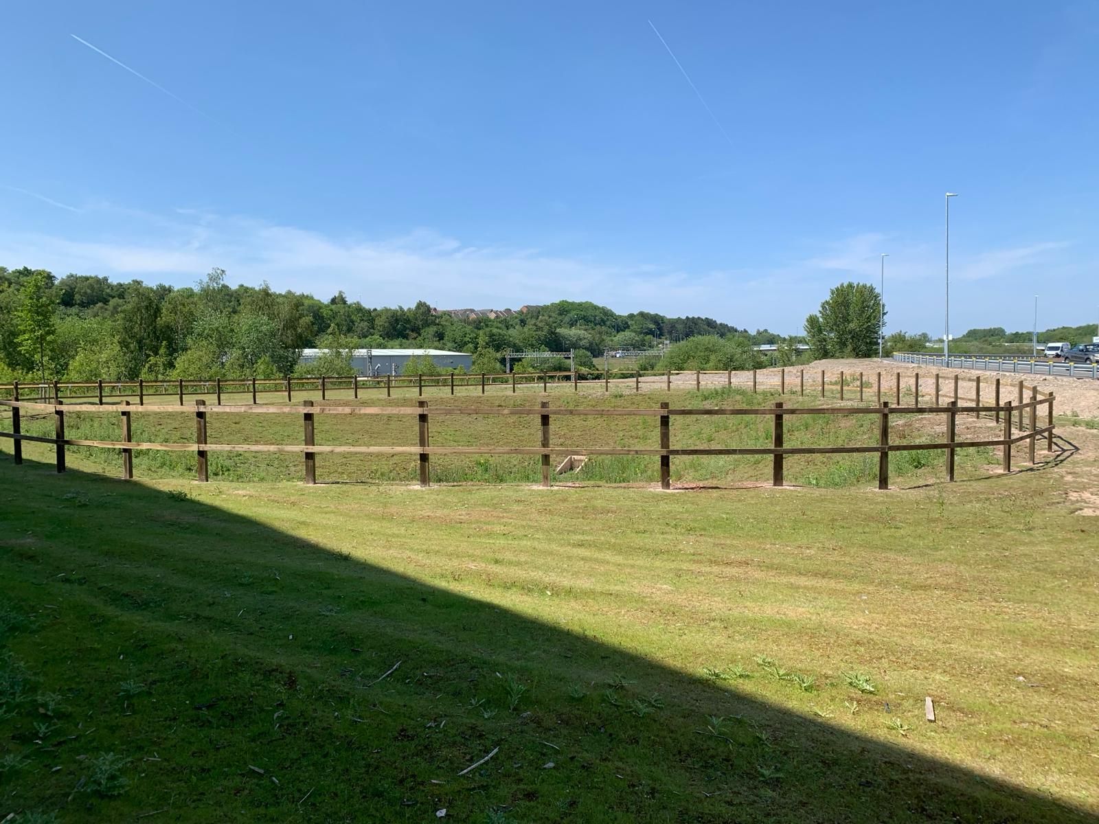 A large grassy field with a wooden fence around it.