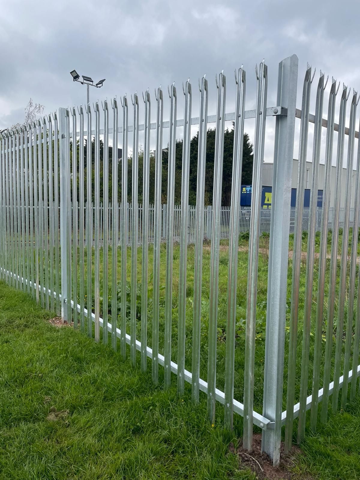 A metal fence is surrounding a grassy field.