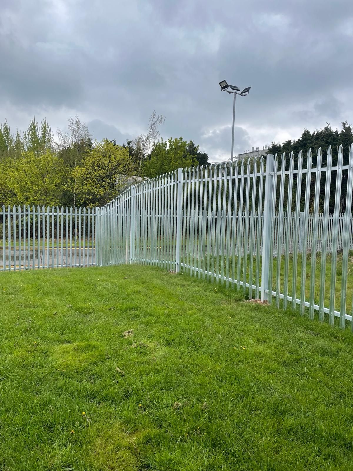 A metal fence surrounds a lush green field.