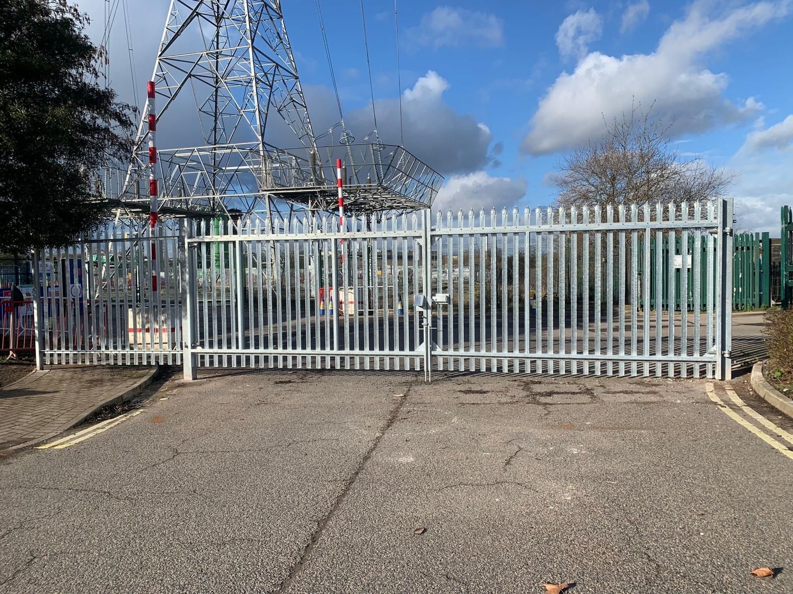 A fence is blocking the entrance to a building with a tower in the background.
