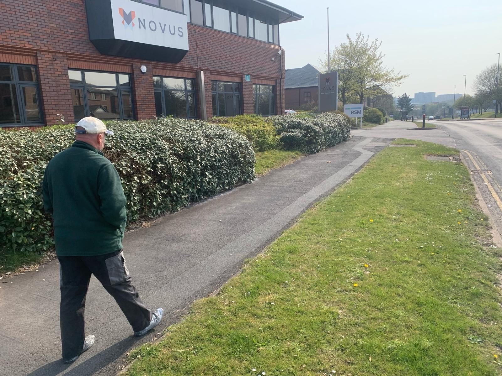 A man is walking down a sidewalk in front of a building that says howles