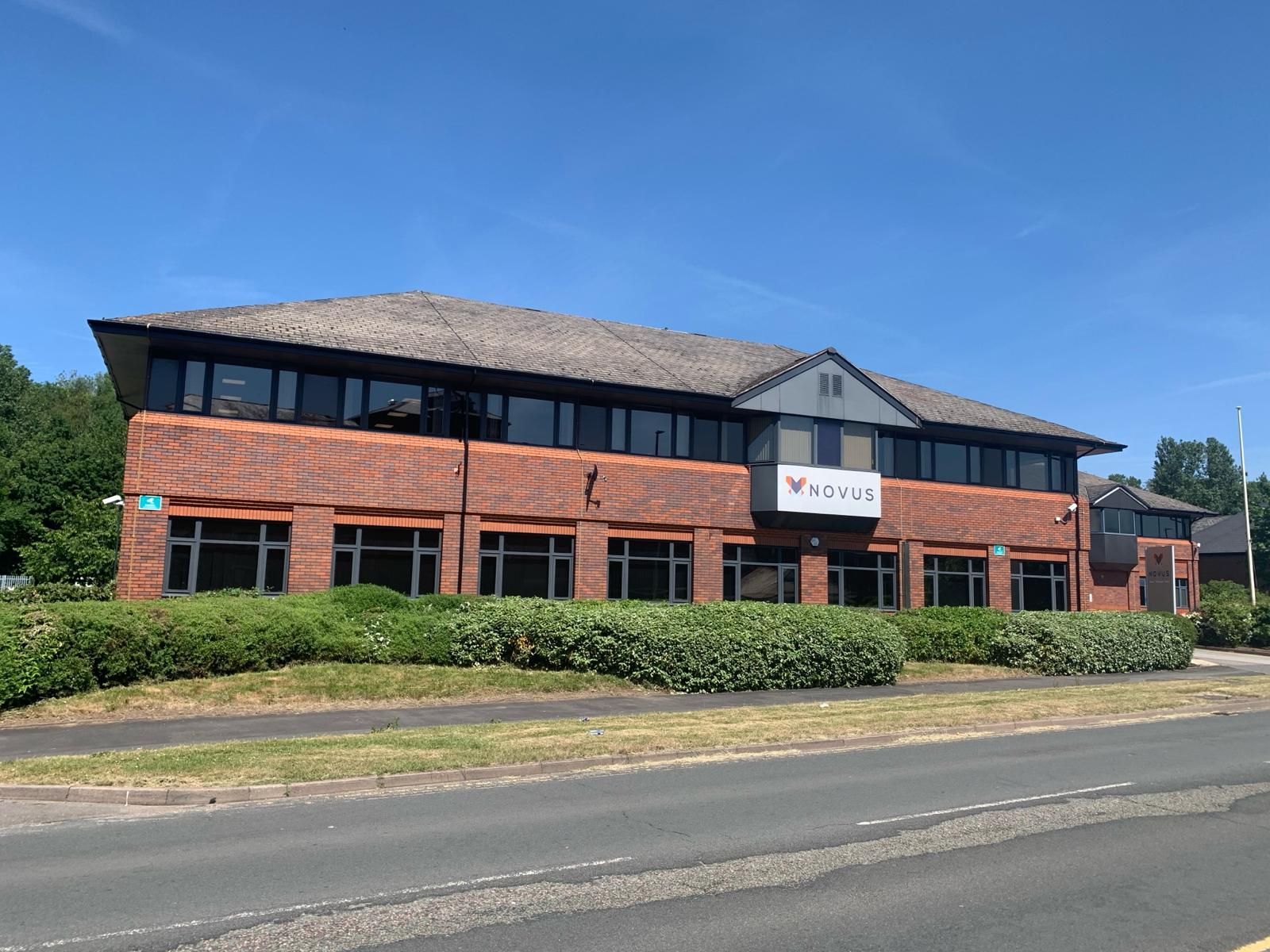 A large brick building with a lot of windows is sitting next to a road.
