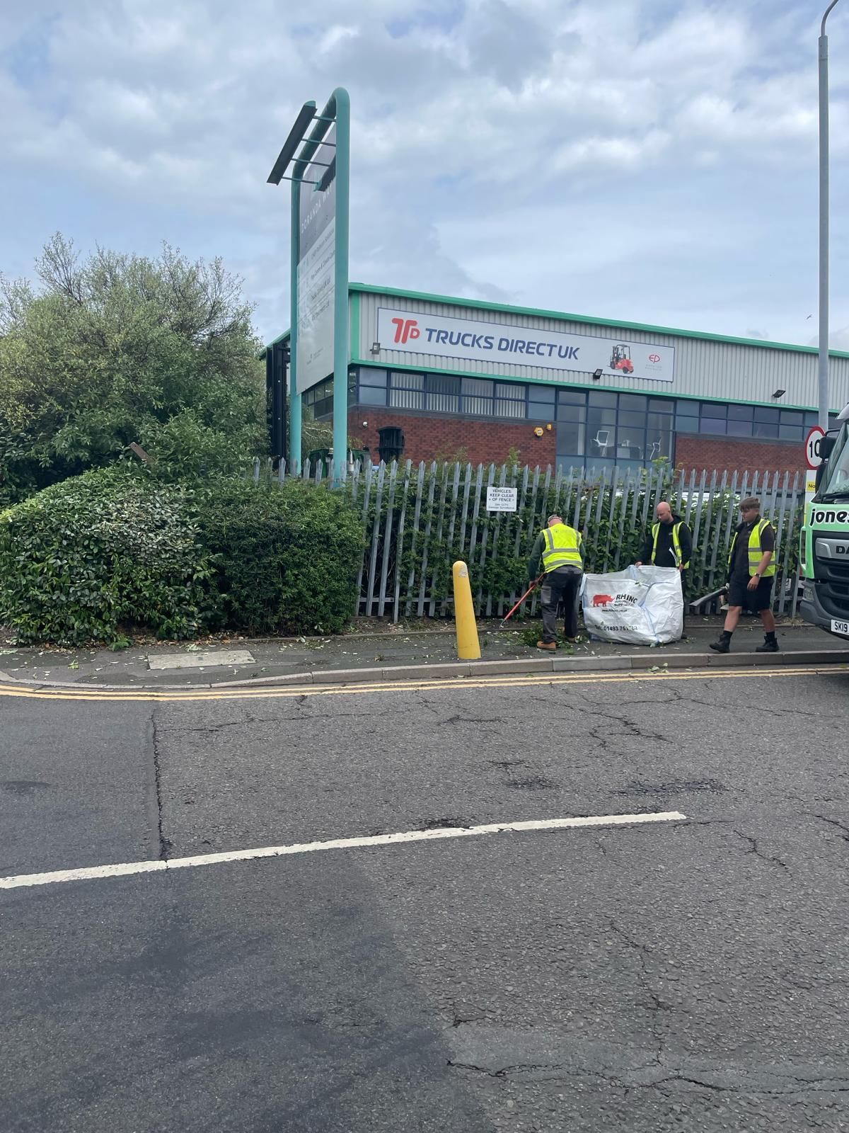 A group of people are standing on the side of the road in front of a building.