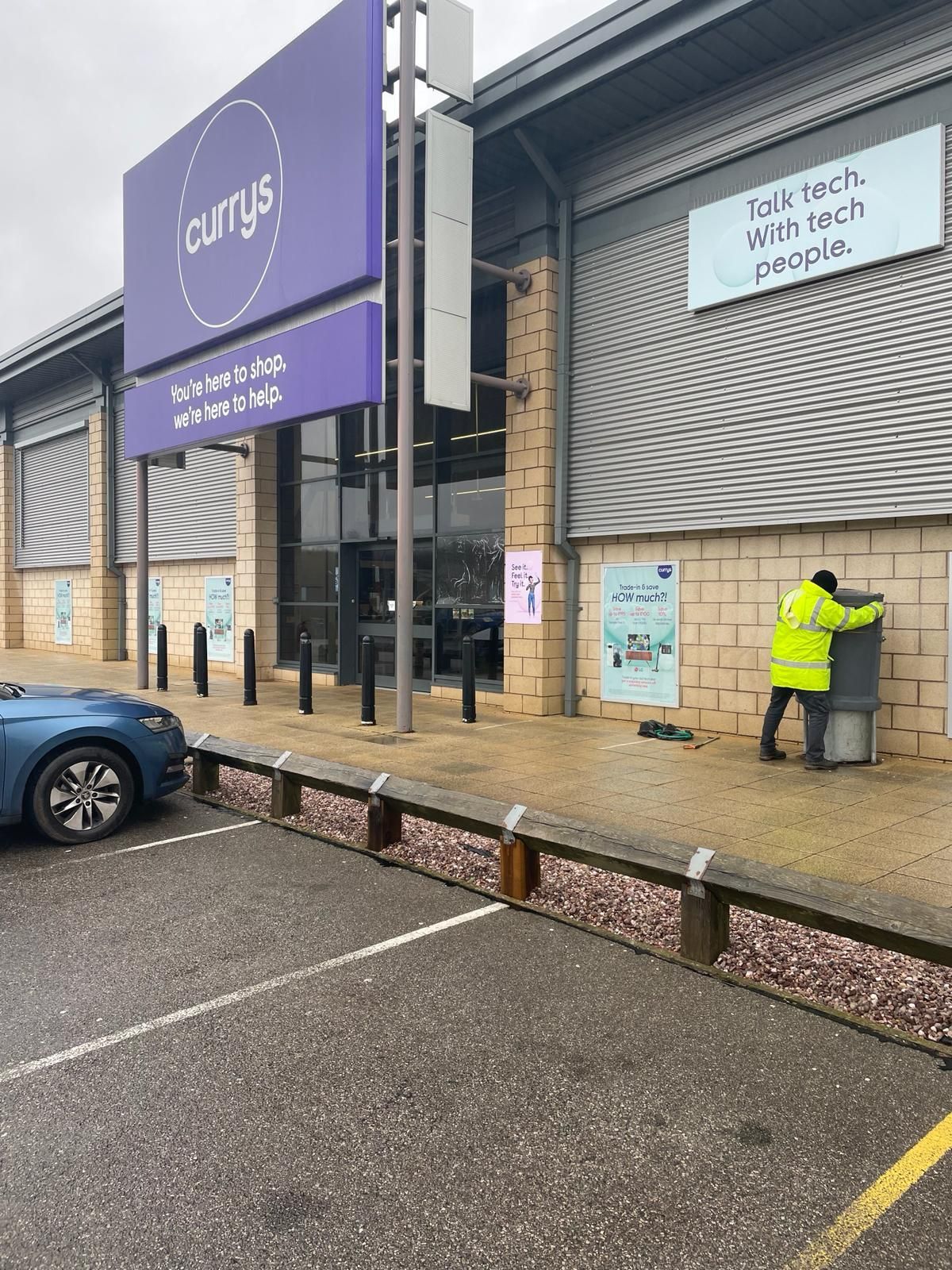 A man in a yellow jacket is standing in front of a building.