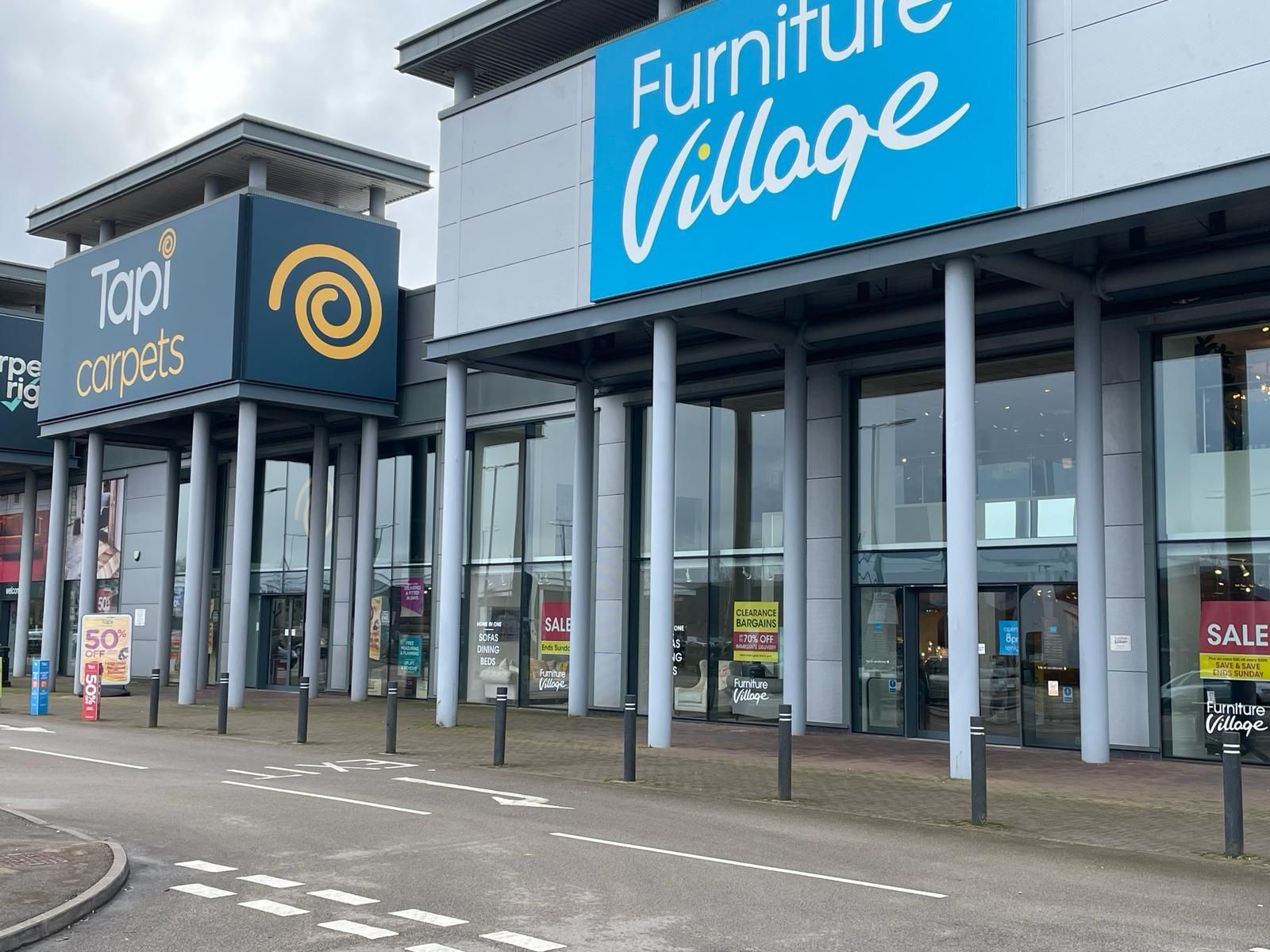 A large building with a blue sign that says furniture village