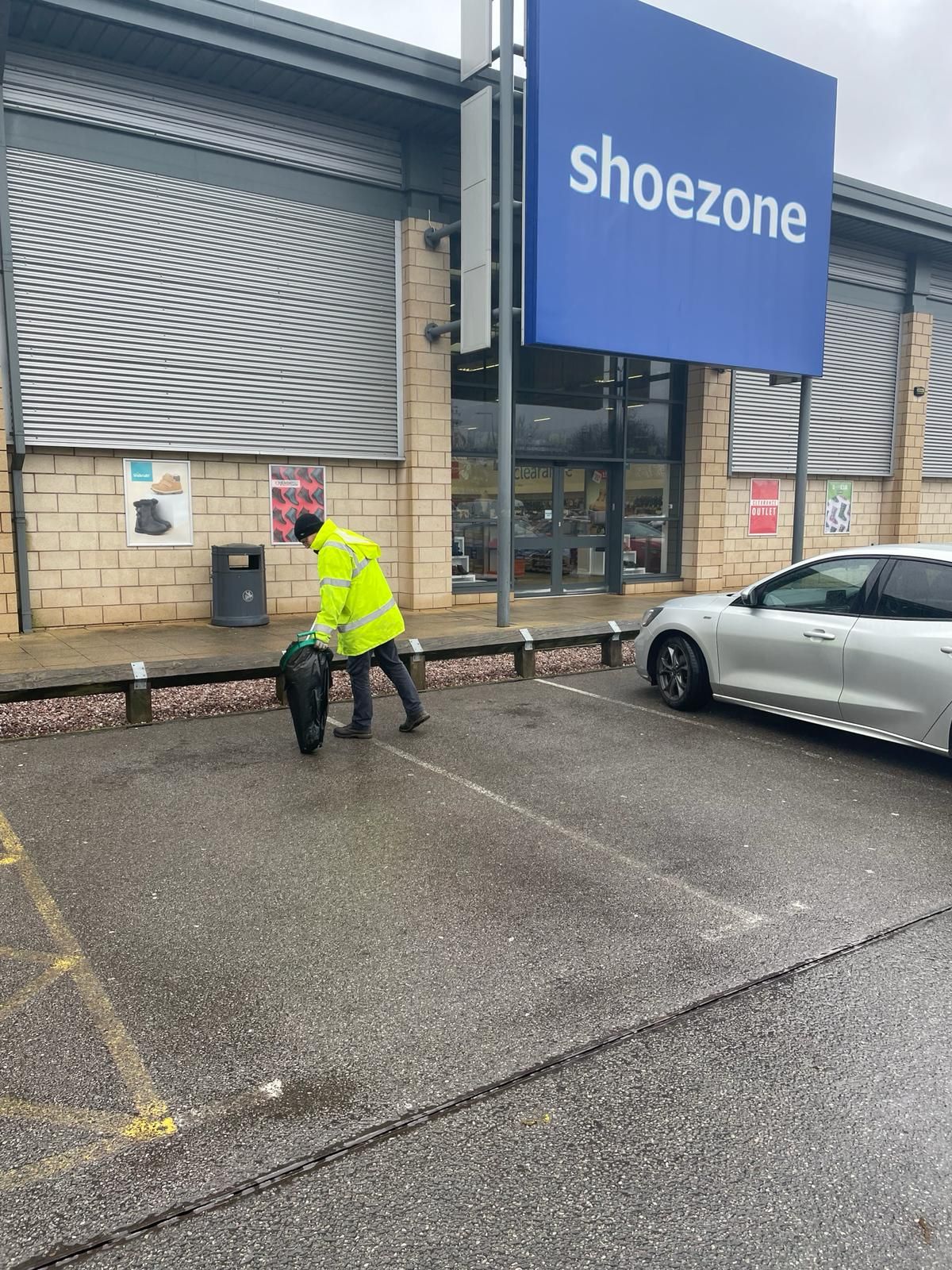 A man is walking a dog in front of a shoezone store.