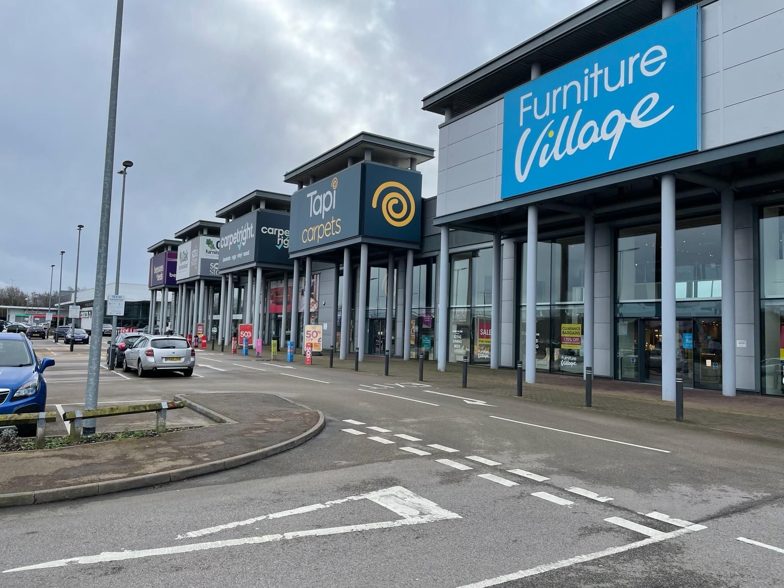 A furniture village store with a lot of cars parked in front of it.