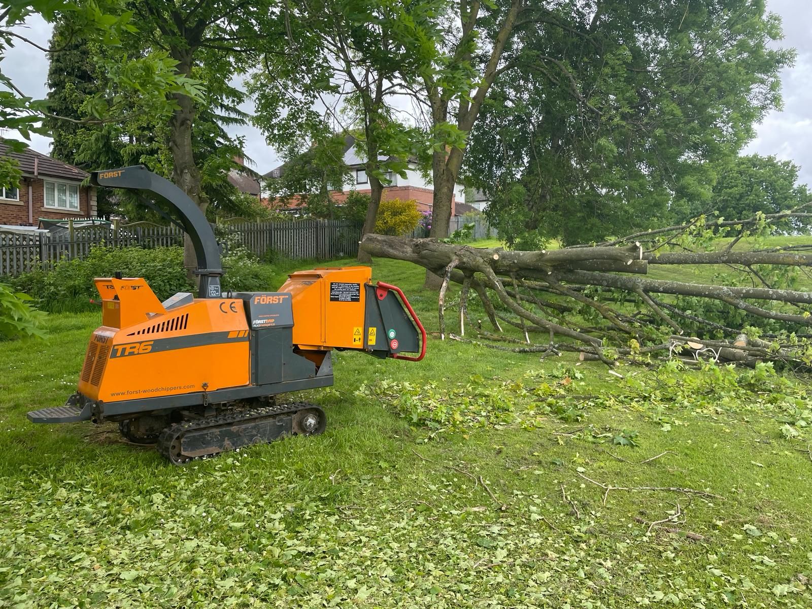 A tree chipper is sitting on top of a lush green field.