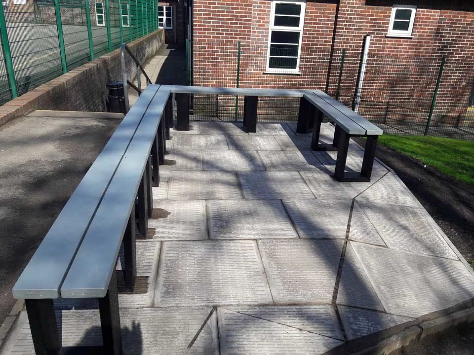 A row of benches on a patio in front of a brick building