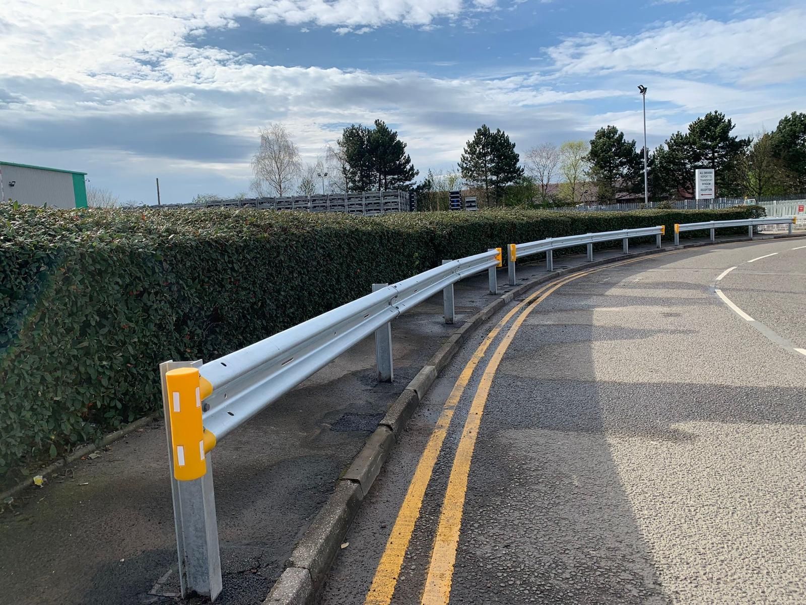A road with a yellow line and a white railing on the side of it.