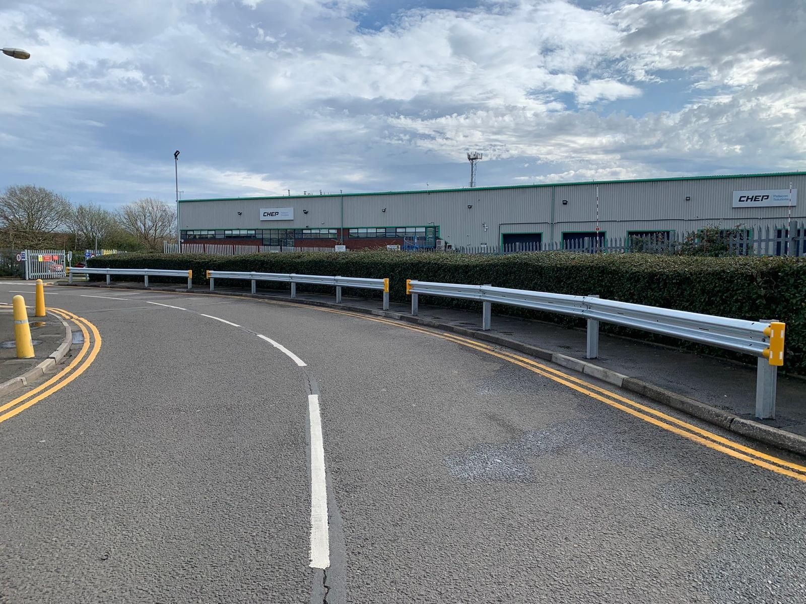 A road with a yellow line on the side of it and a building in the background.