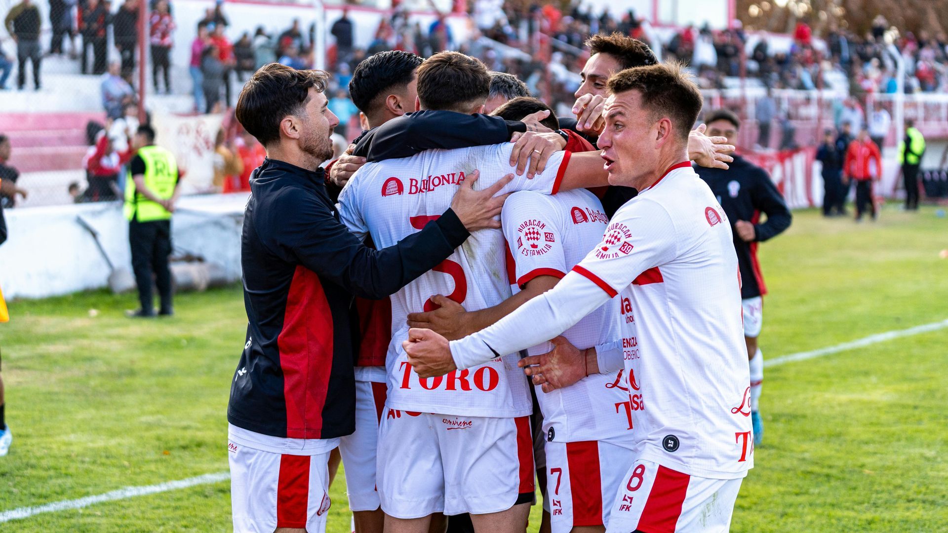 A group of soccer players are hugging each other on a field.