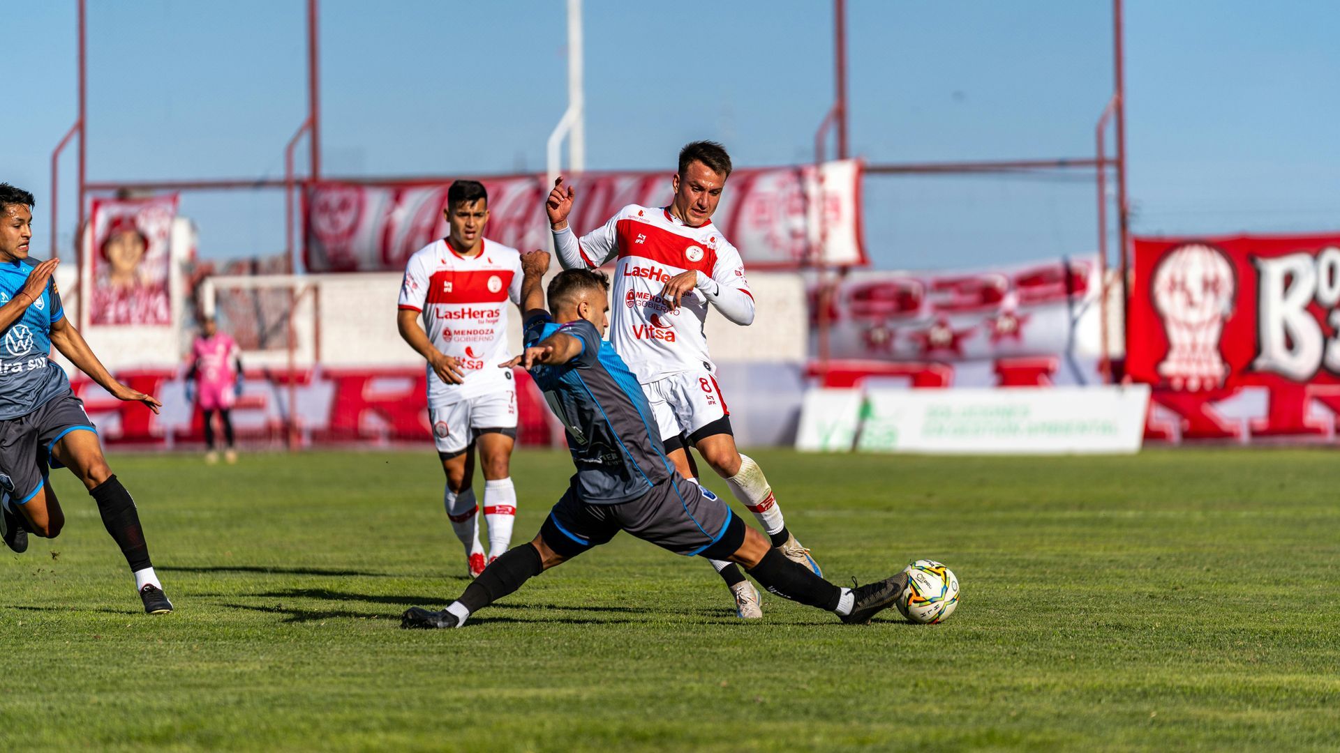 A group of soccer players are playing a game of soccer on a field.