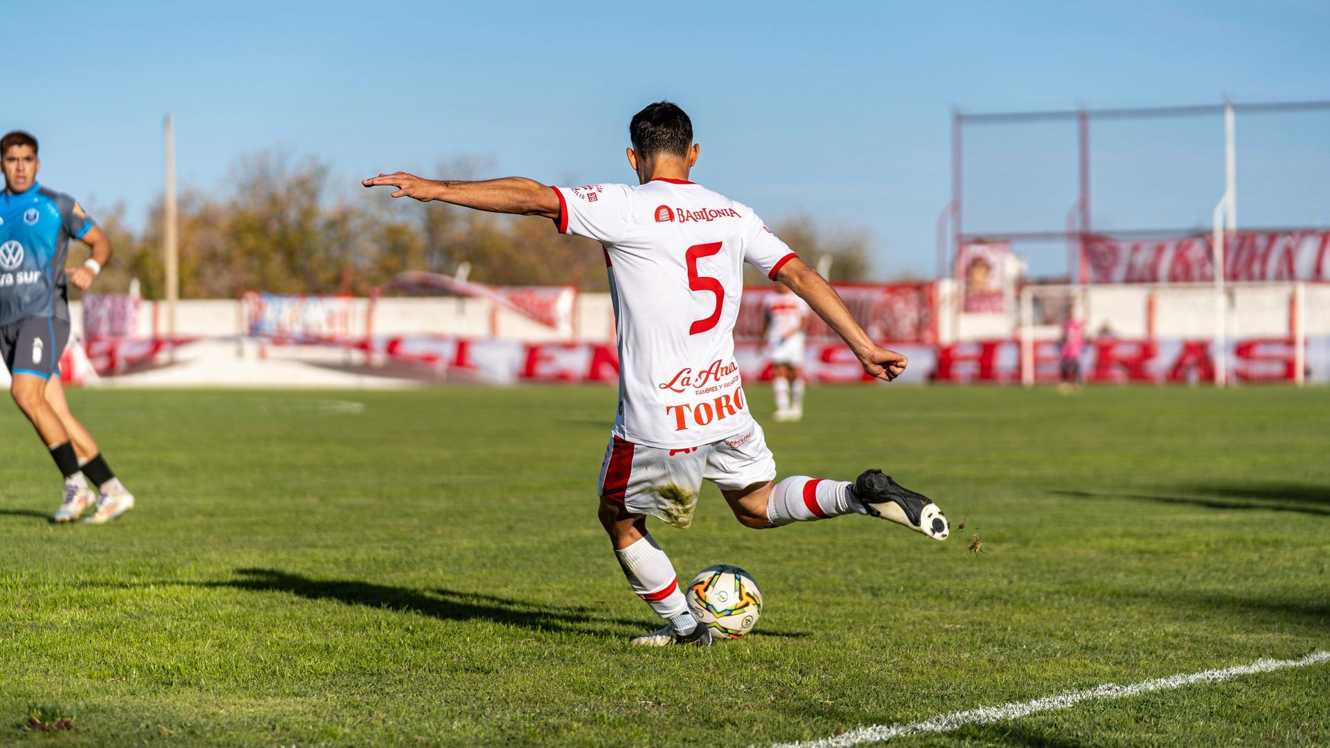 A soccer player is kicking a soccer ball on a field.