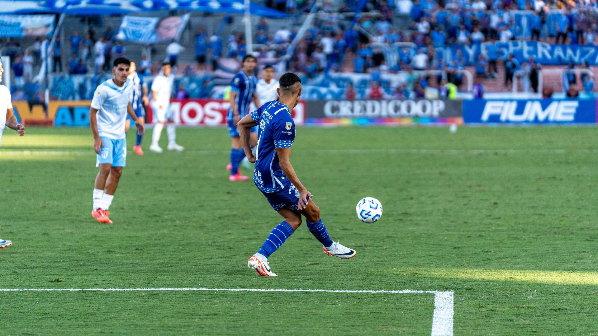 A soccer player is kicking a soccer ball on a field.
