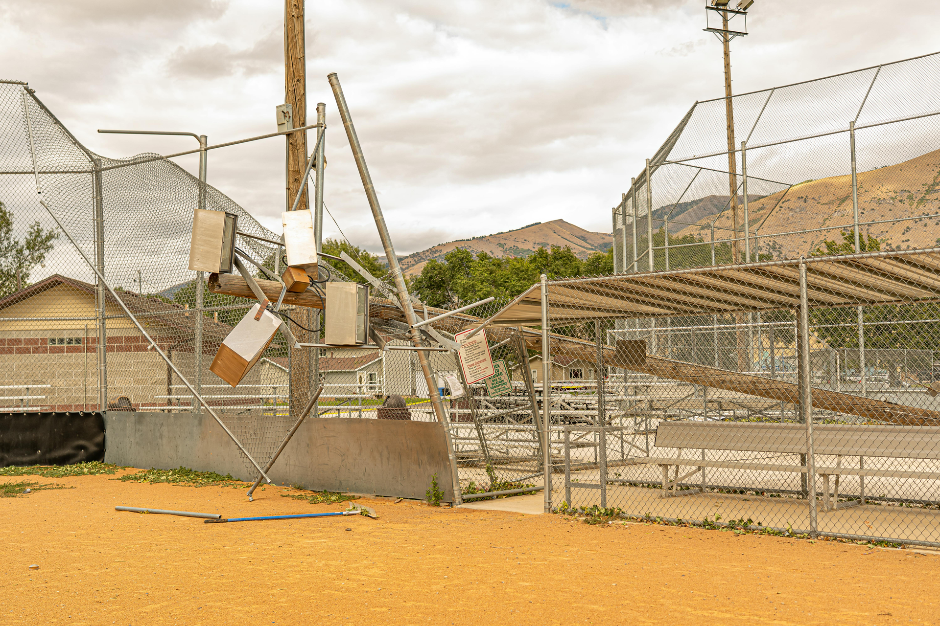 A baseball field with a fence and bleachers in the background.