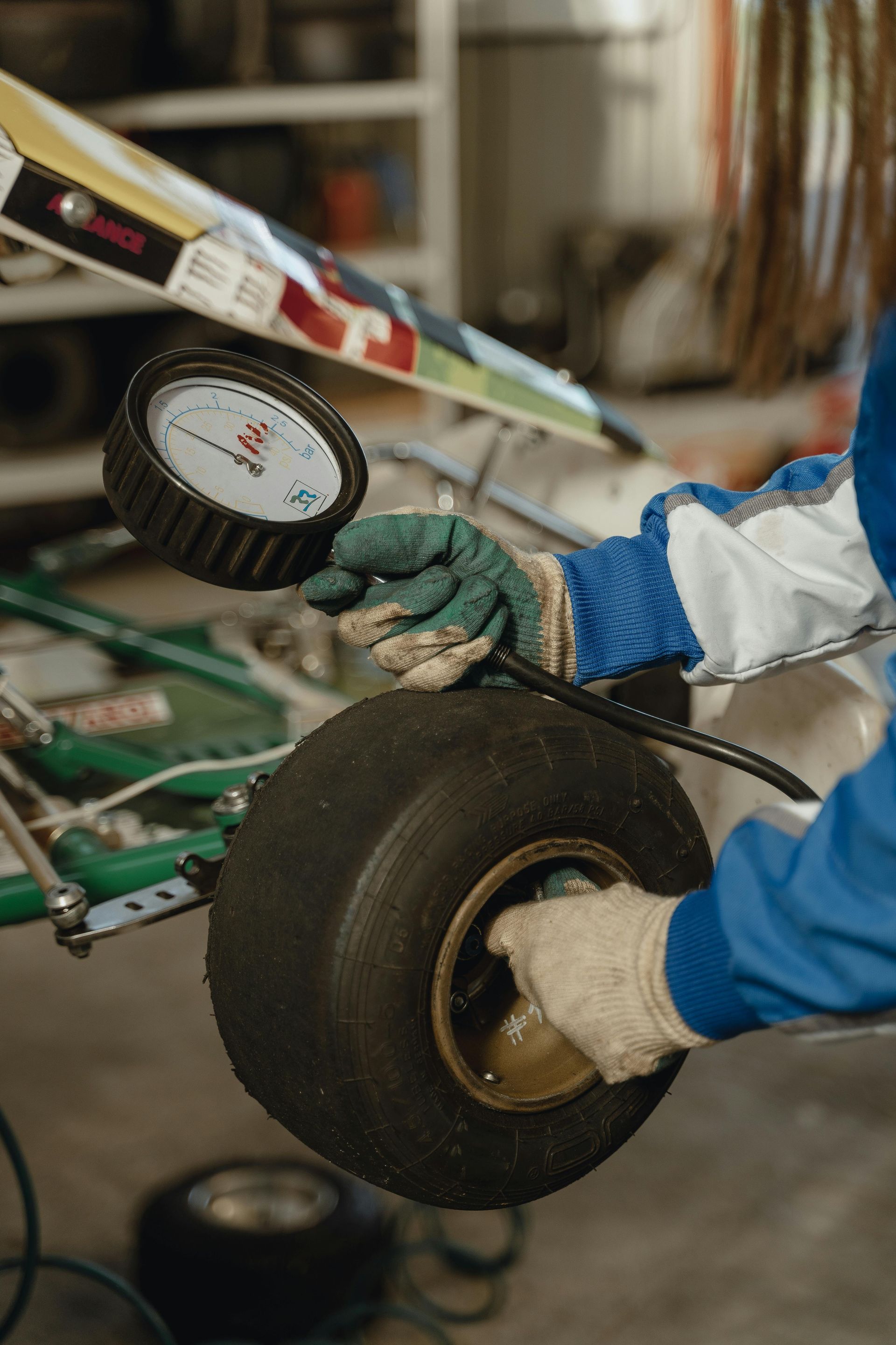 A person is checking the pressure of a tire on a go kart.