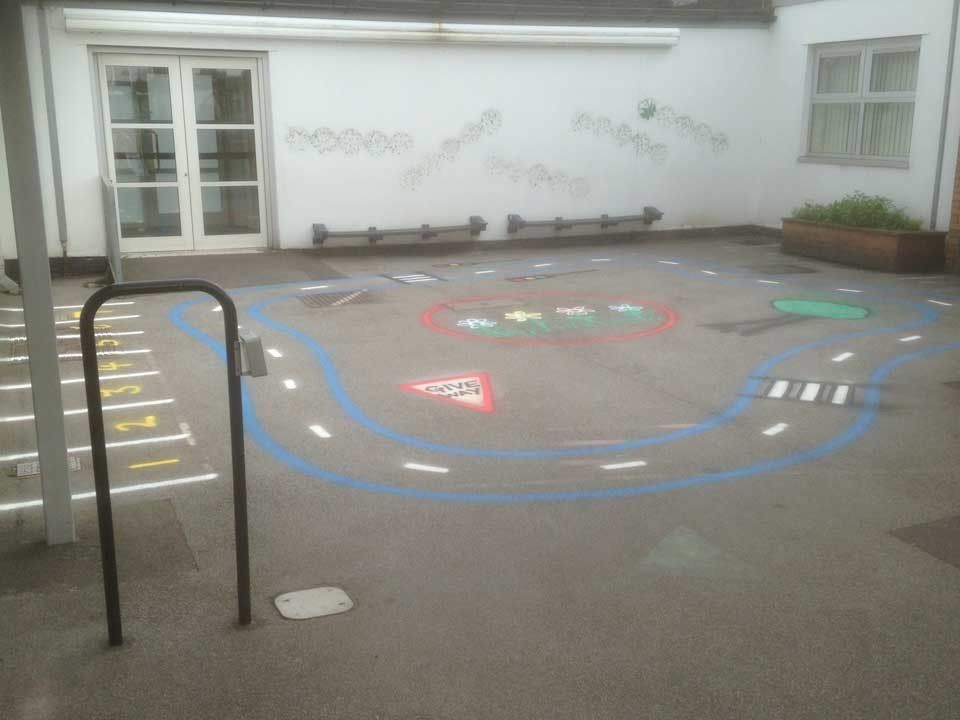 A playground with chalk drawings on the ground and a fence