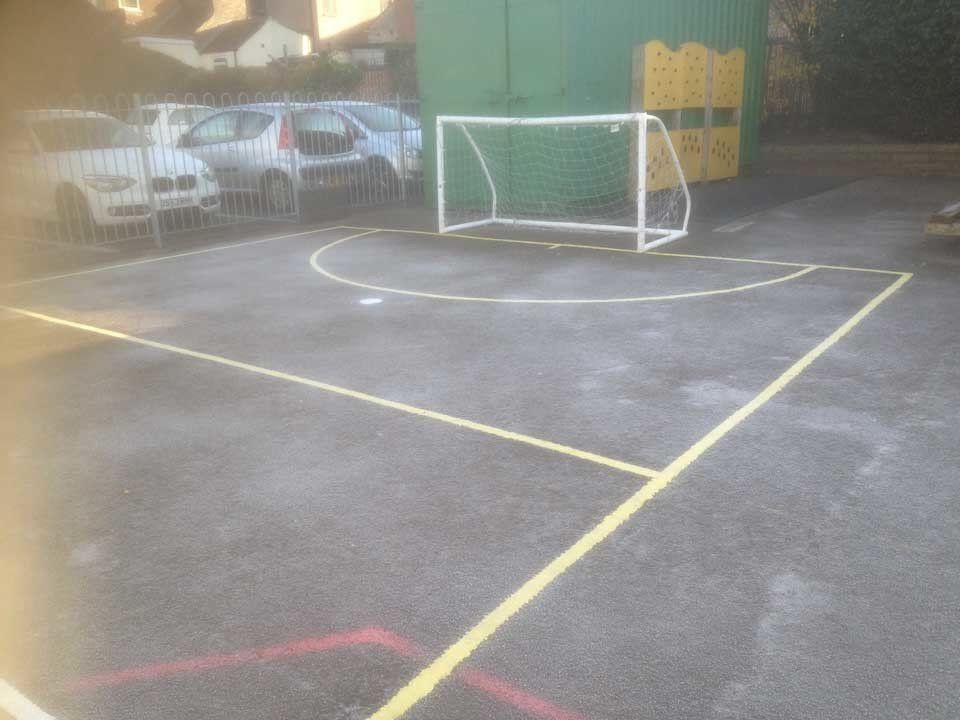 A soccer goal is in the middle of a basketball court.