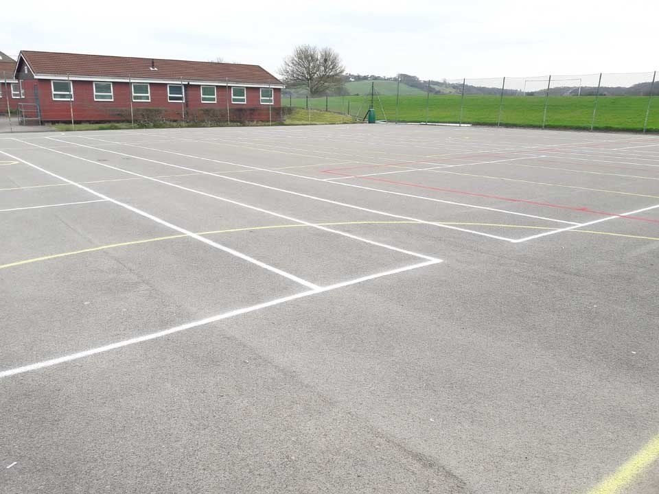 An empty parking lot with a red building in the background