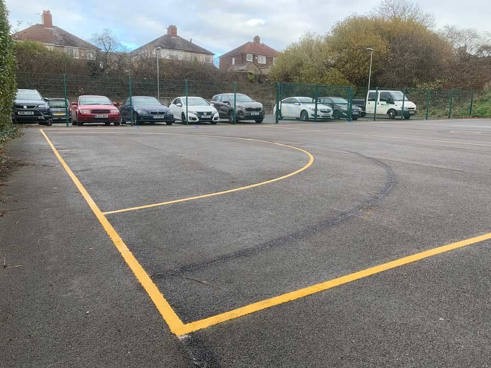 A row of cars are parked in a parking lot with a yellow line.