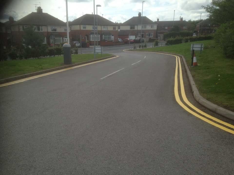 A road with yellow lines on it and houses in the background