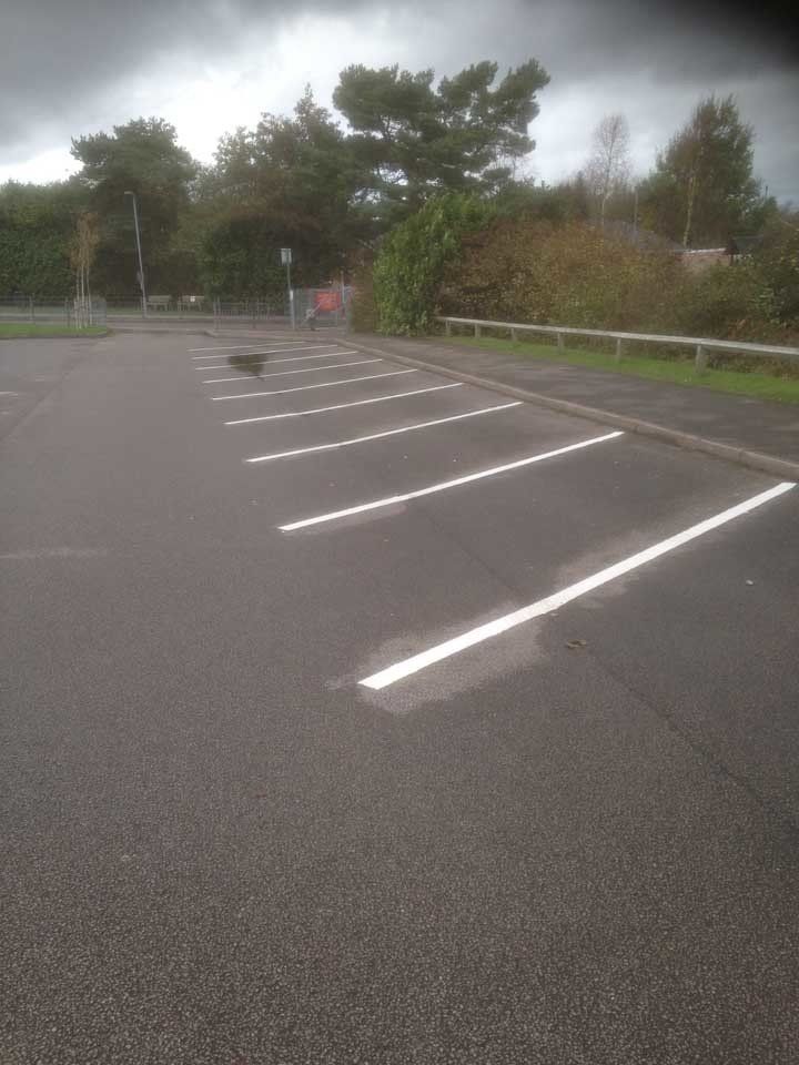 A parking lot with white lines on it and trees in the background