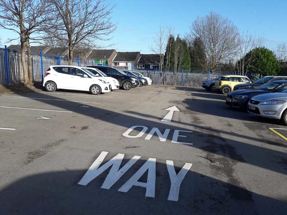 A parking lot with a one way sign painted on the ground