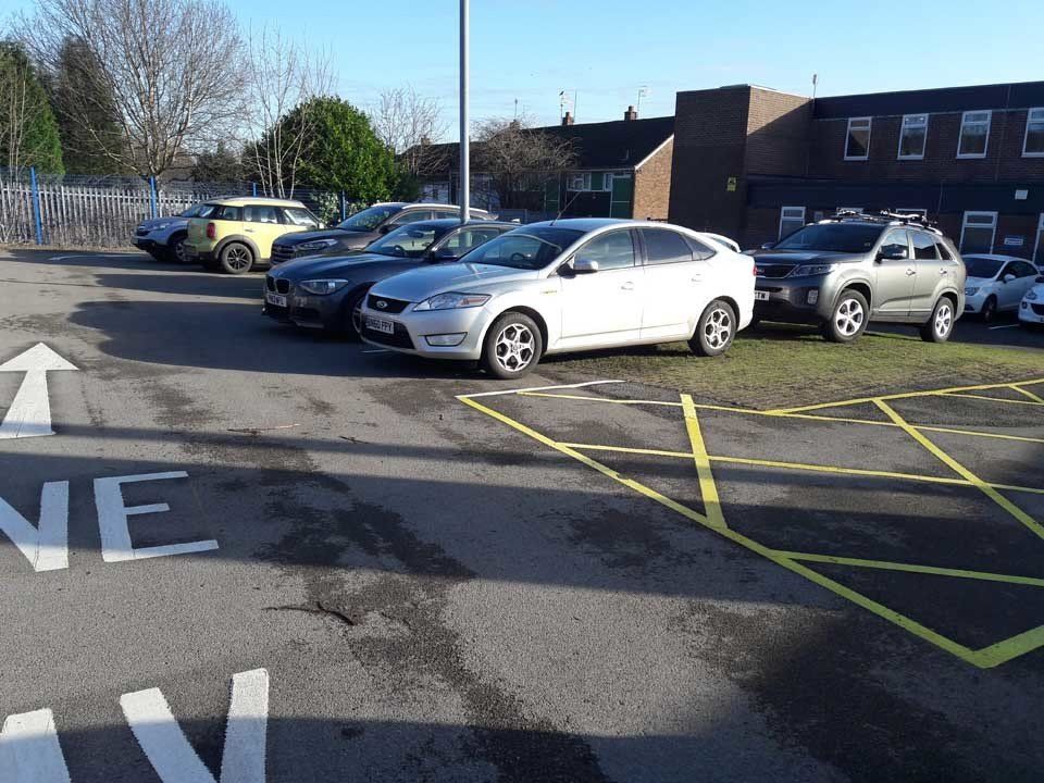 A row of cars are parked in a parking lot.