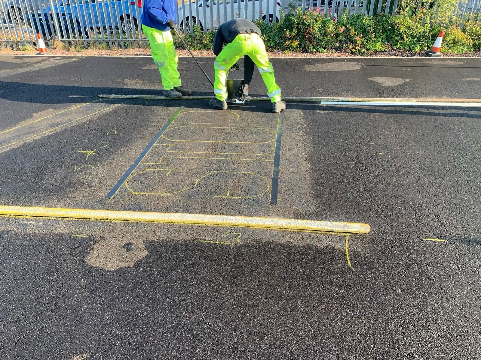 Two construction workers are working on a road.