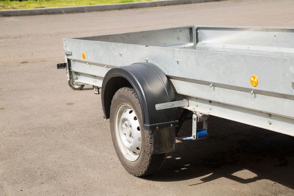 A small trailer is parked on the side of the road.