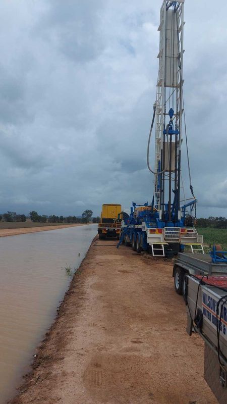 Oil Rig Alongside a Waterway, With Trucks and Cloudy Sky — Wilson's Drilling in South Kolan, QLD