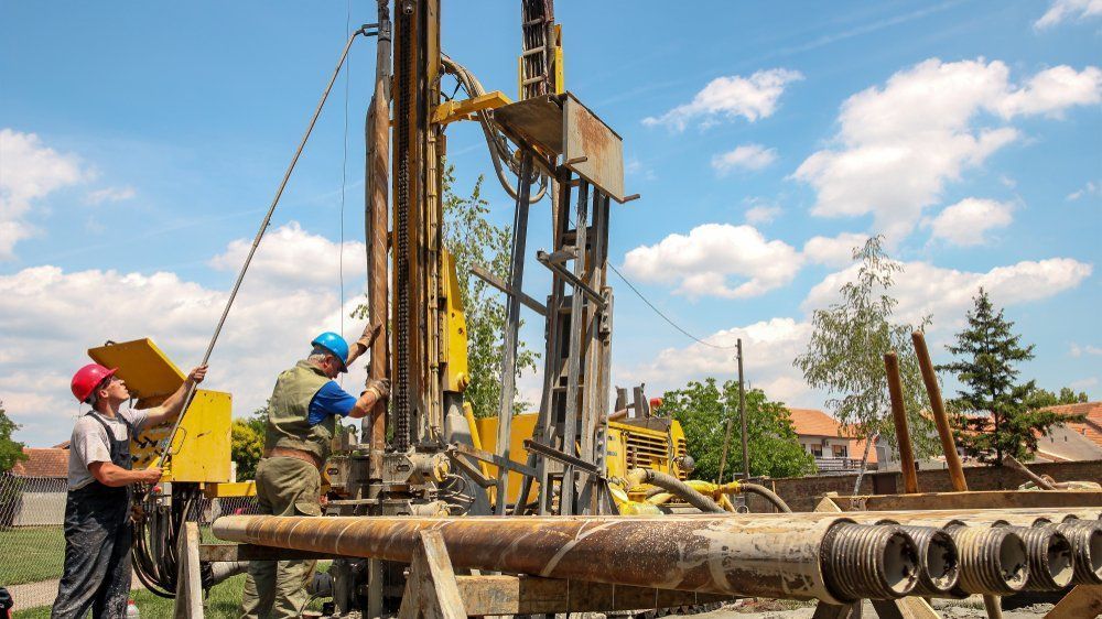 Two Workers Operating a Yellow Drilling Rig Outdoors on a Sunny Day — Wilson's Drilling in South Kolan, QLD