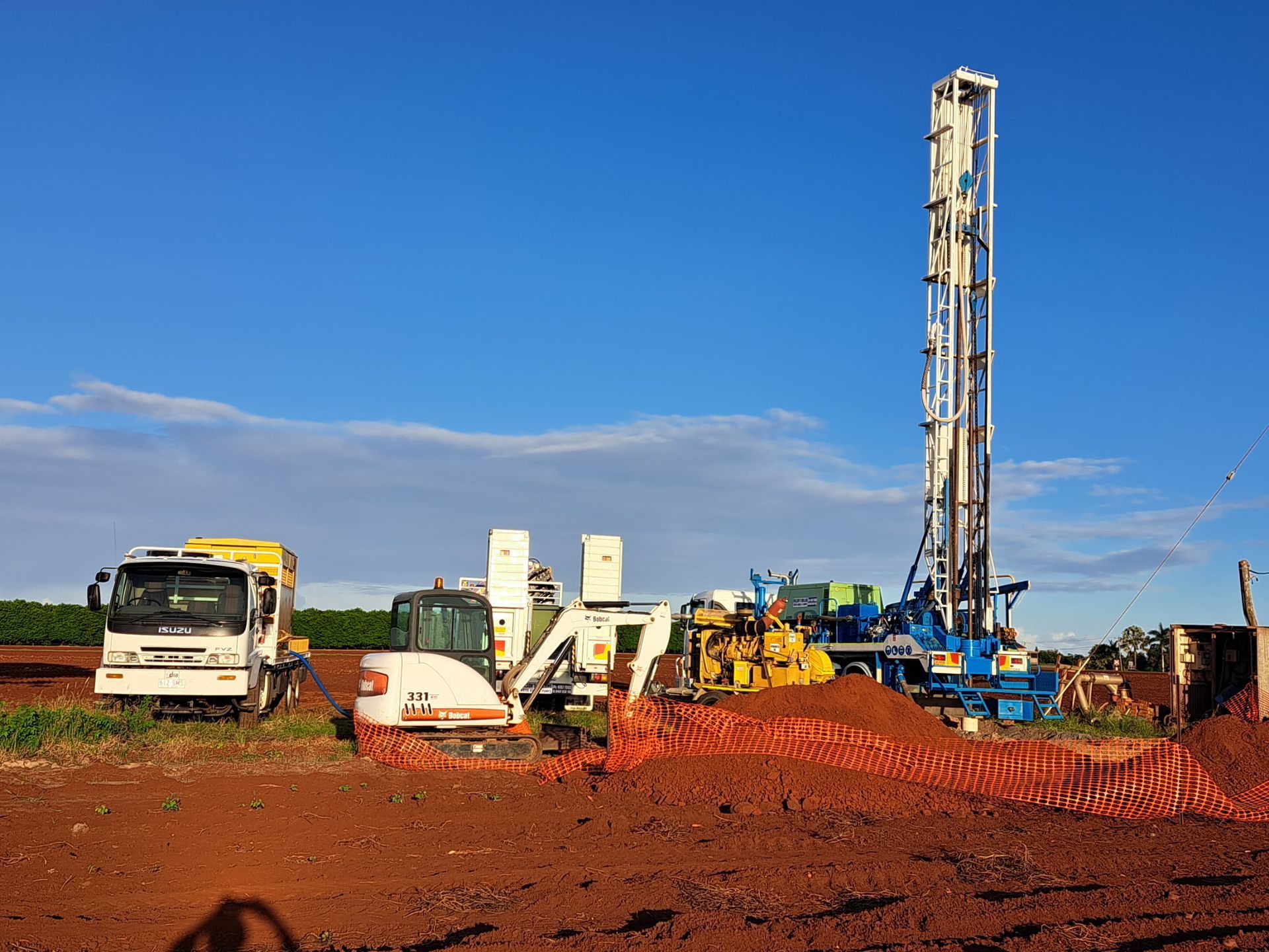 Drilling Rig with Support Vehicles on A Red Dirt Field Under a Blue Sky — Wilson's Drilling in South Kolan, QLD