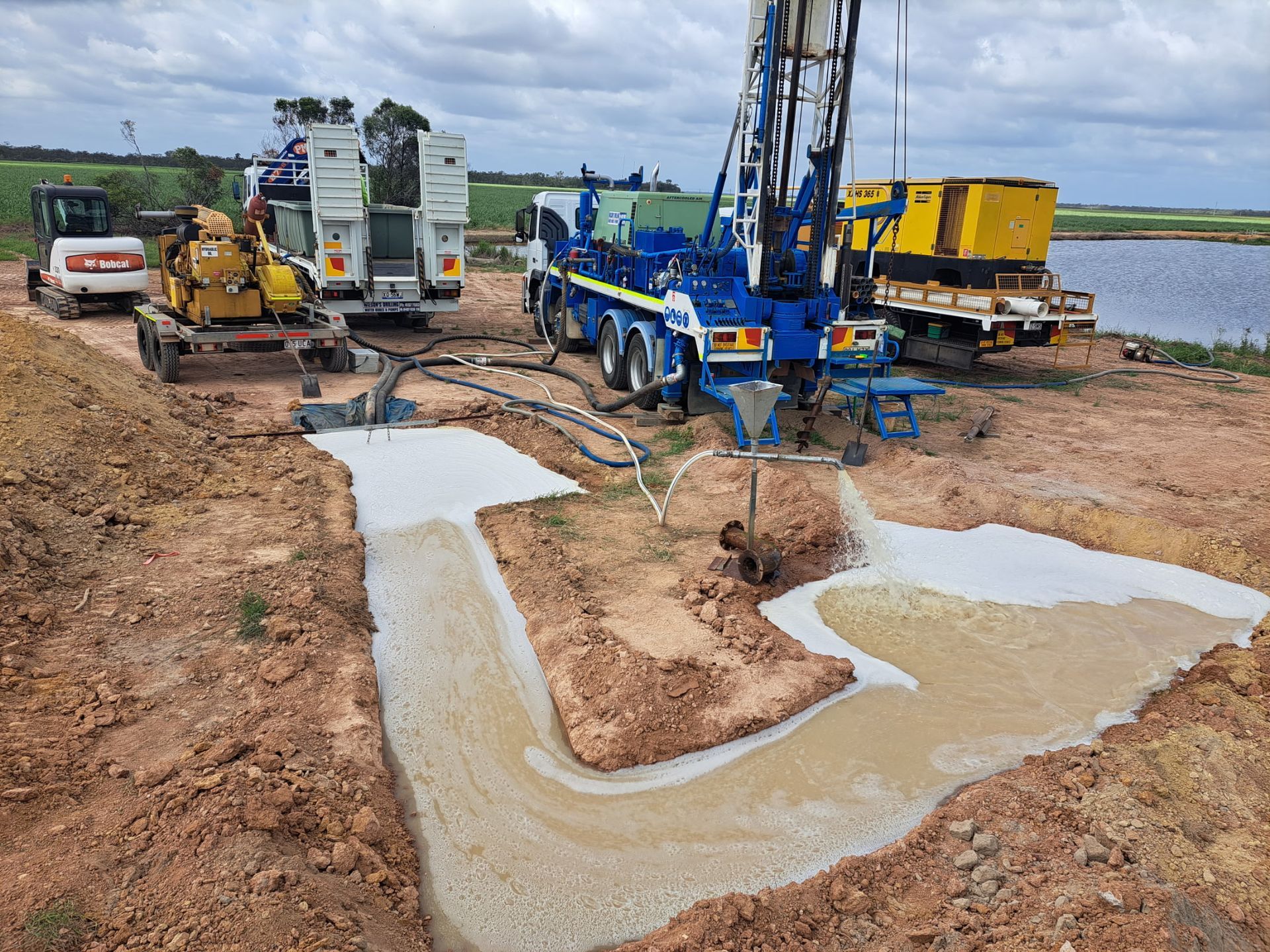 Drilling Rig and Support Vehicles on A Construction Site Next to A Body of Water — Wilson's Drilling in South Kolan, QLD