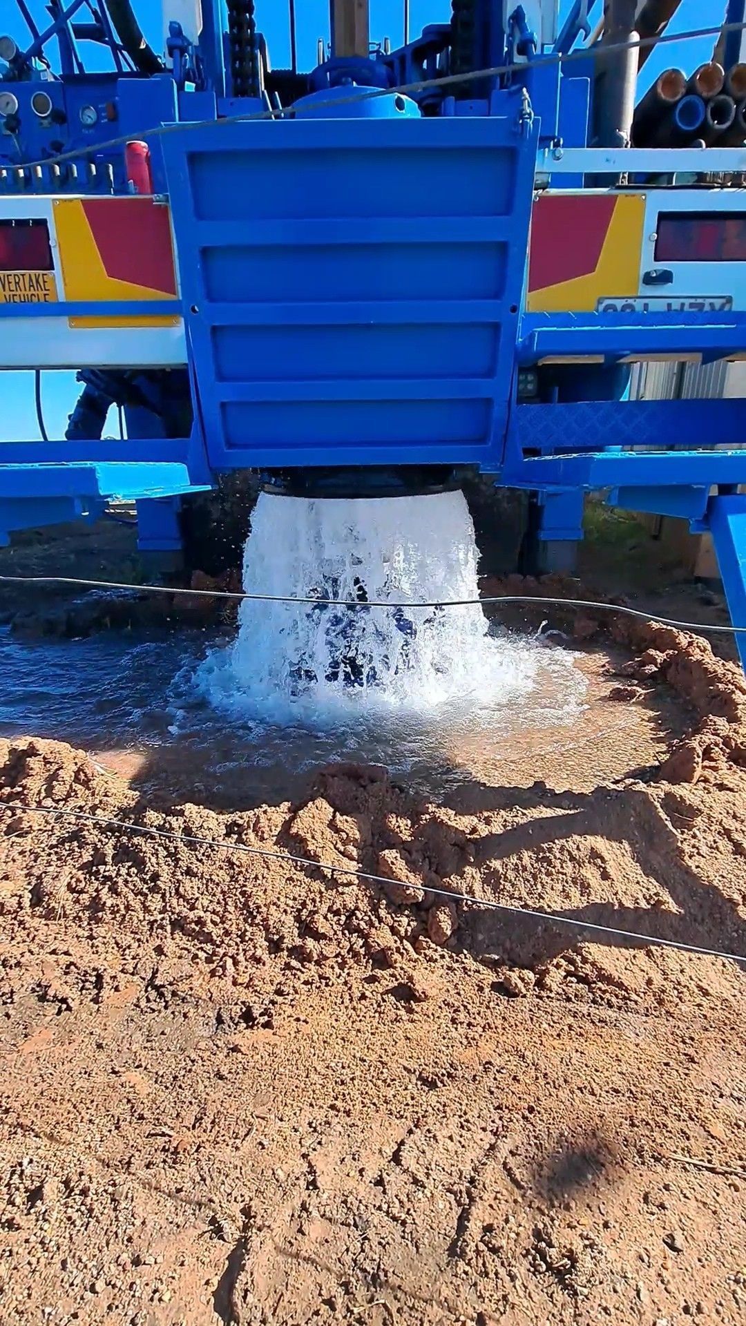 Blue Machine Spraying Water Onto Reddish-brown Dirt — Wilson's Drilling in South Kolan, QLD
