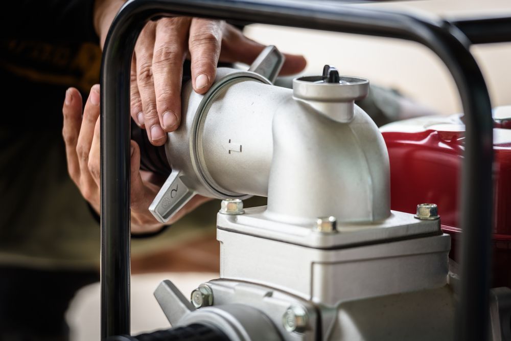 Person Attaching a Hose to a Silver Water Pump, Hands Visible — Wilson's Drilling in South Kolan, QLD