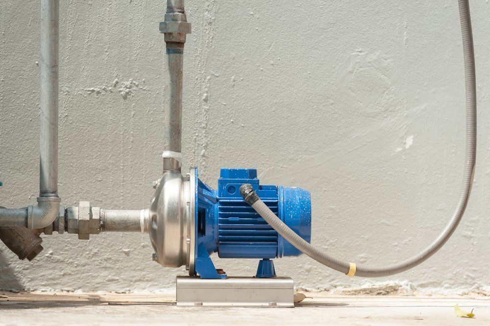 Blue Water Pump Attached to Pipes Against a Light Gray Wall — Wilson's Drilling in Bundaberg, QLD
