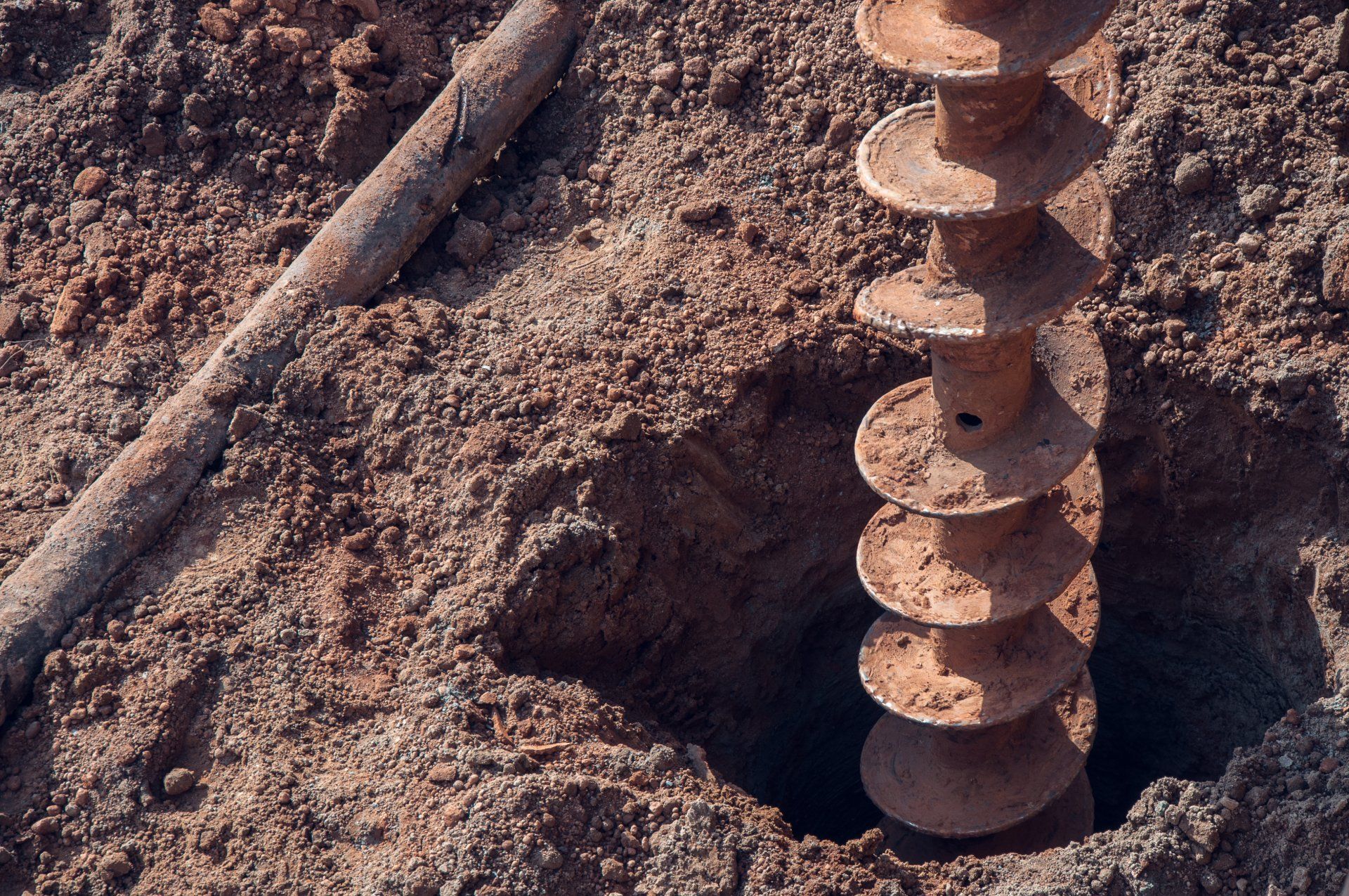 An Auger Drilling Into Reddish-brown Soil — Wilson's Drilling in Childers, QLD