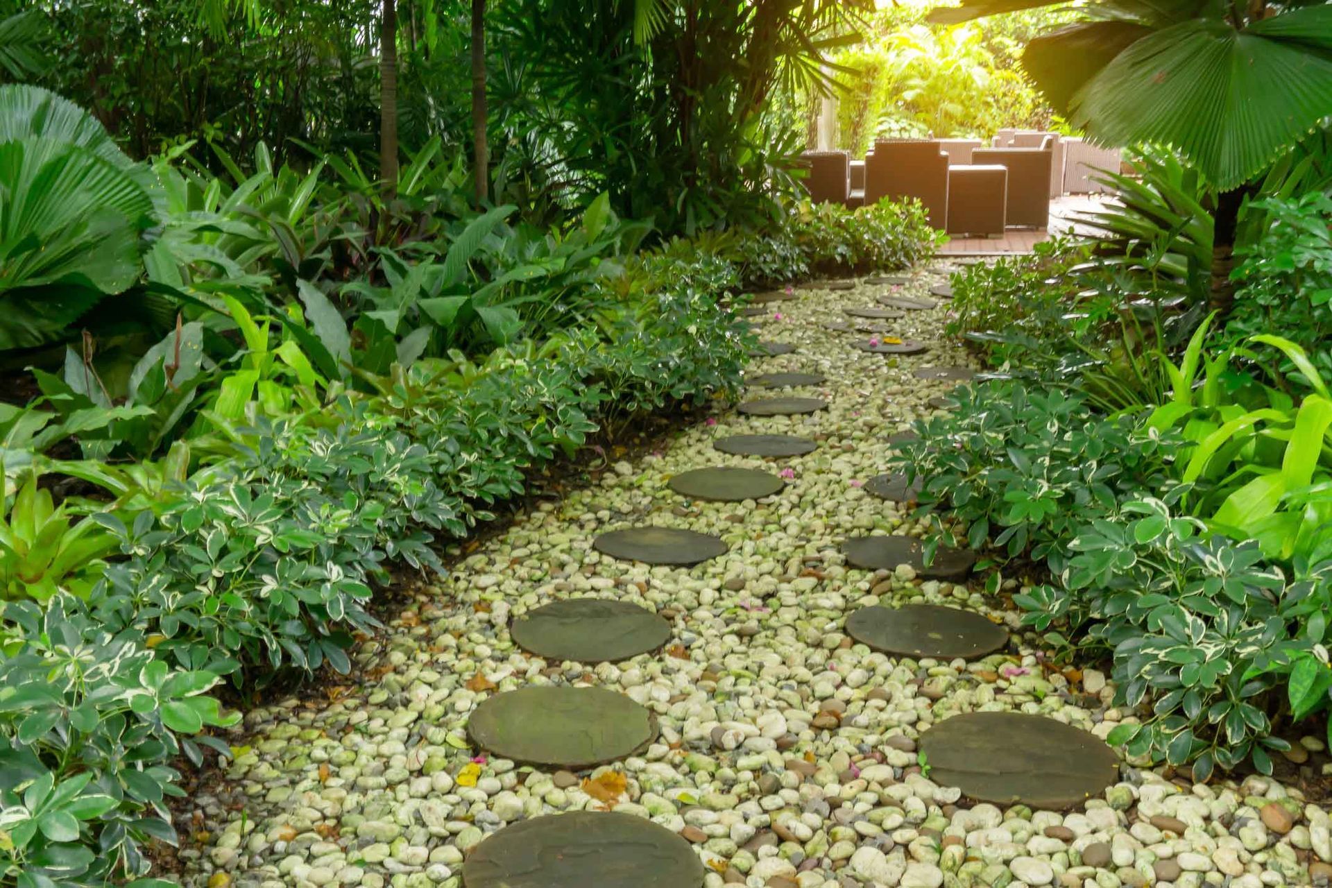 Stone pathway through lush green garden with stepping stones and light brown gravel.