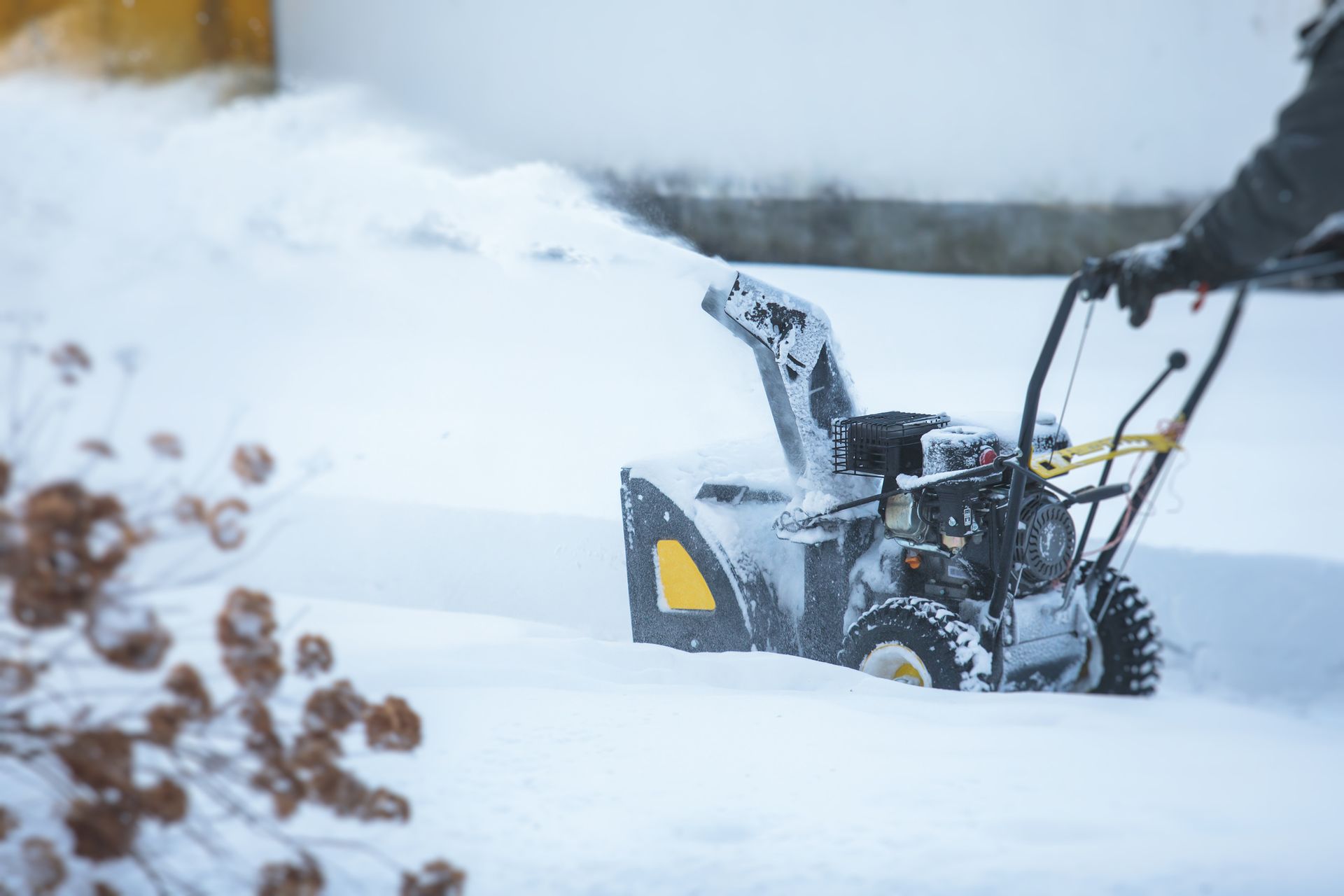 Person using a snowblower to clear snow from a driveway.