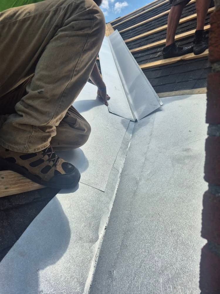 Person on a roof installing metal flashing around a chimney.